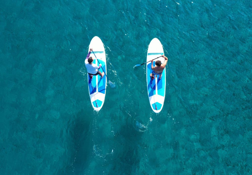 Two people on a paddle board, shot from the drone