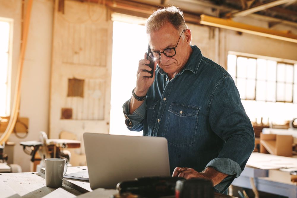 Senior business owner talking over the phone in his shop