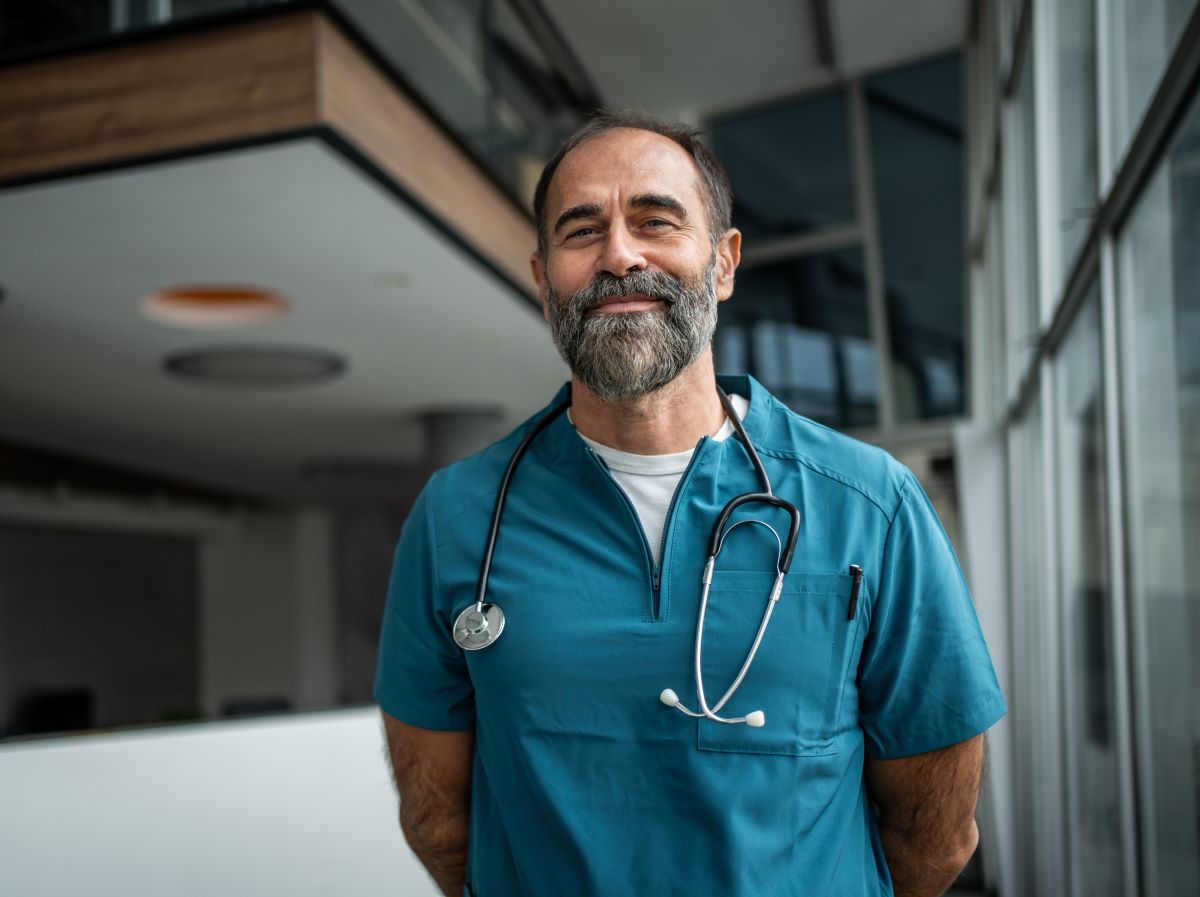 Experienced male doctor smiling in hospital corridor