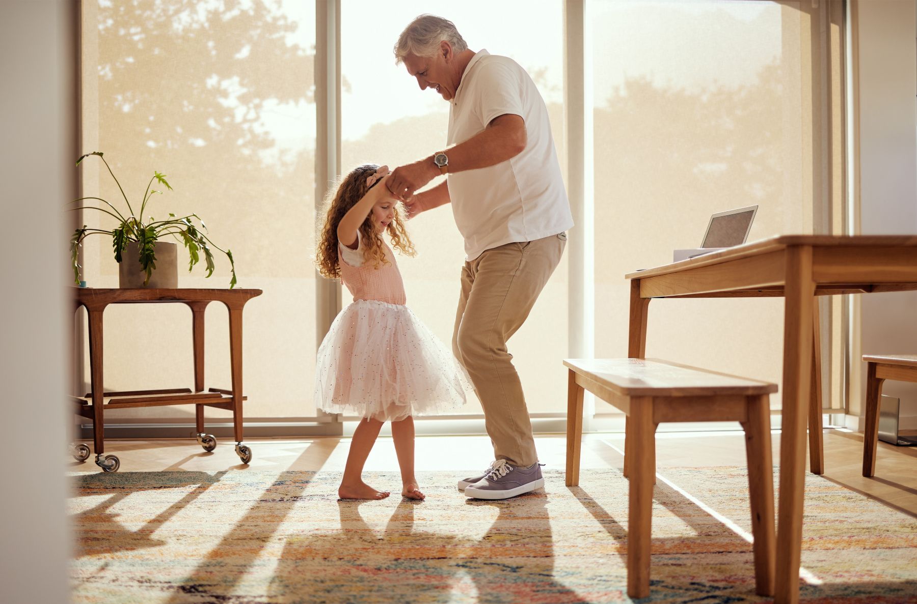 Grandfather, girl and dance holding hands in living room